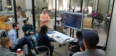 Students sitting around a computer, learning at San Diego Code Scool