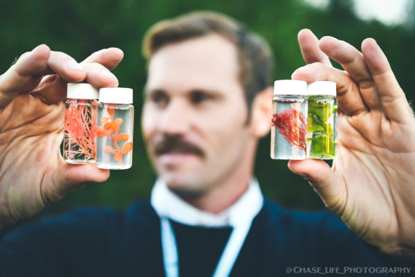 Brant Chlebowski holding up small jars containing seaweed