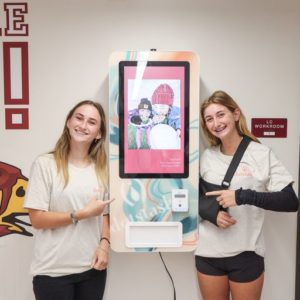 Two girls posting with Dotstash dispenser